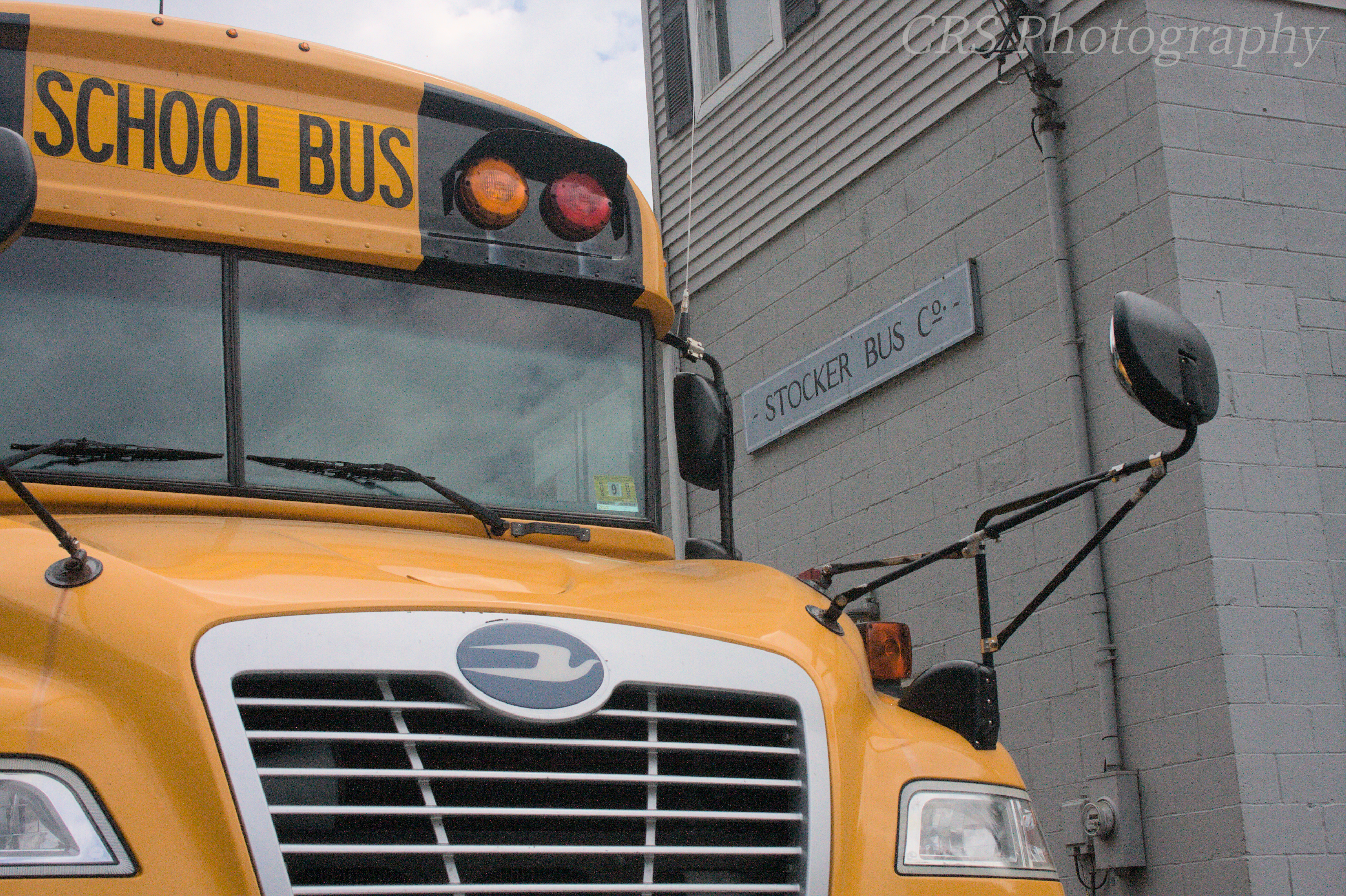 A yellow school bus parked near a building labeled "Stocker Bus Co."